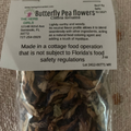 Packaged butterfly pea flowers with a label on a textured surface