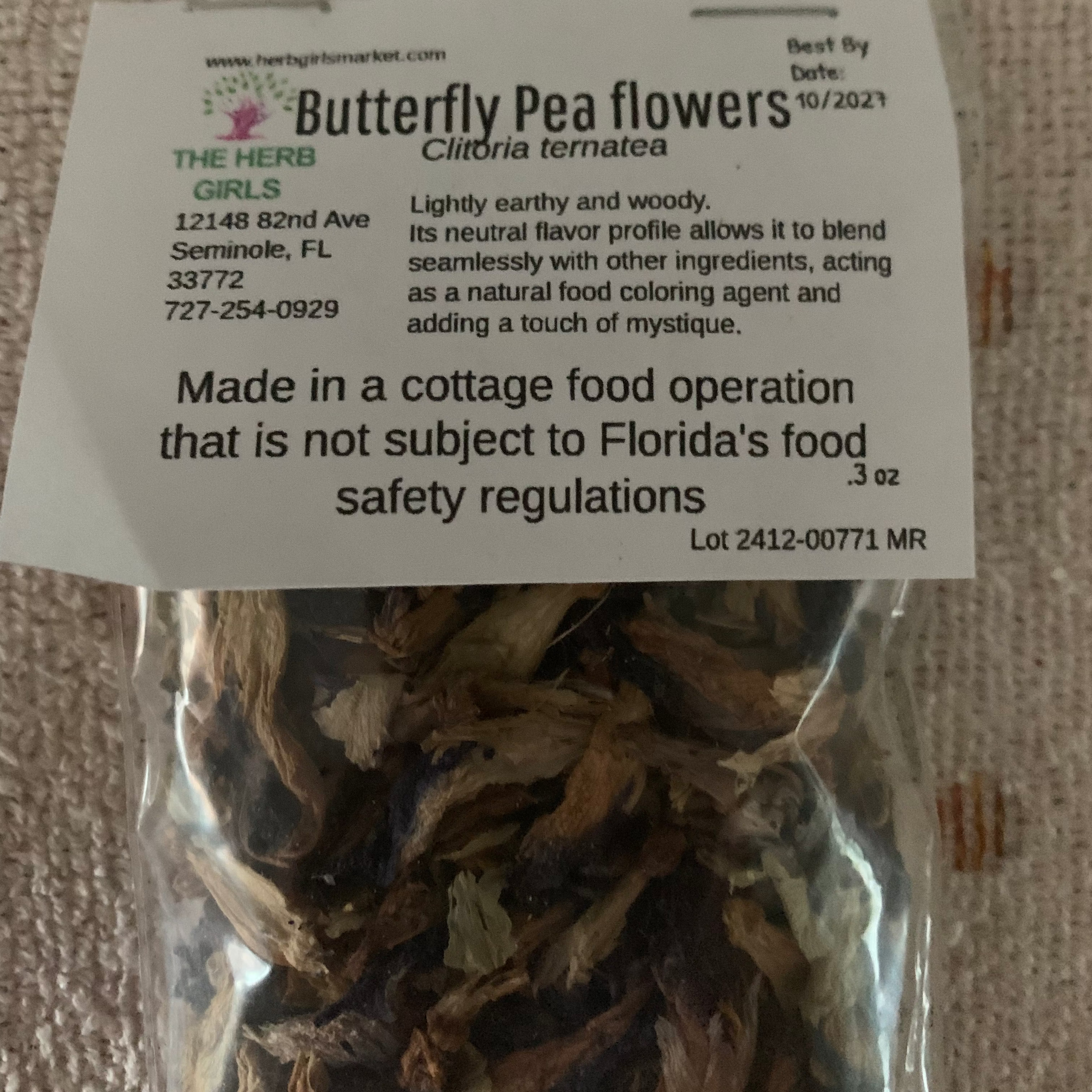 Packaged butterfly pea flowers with a label on a textured surface