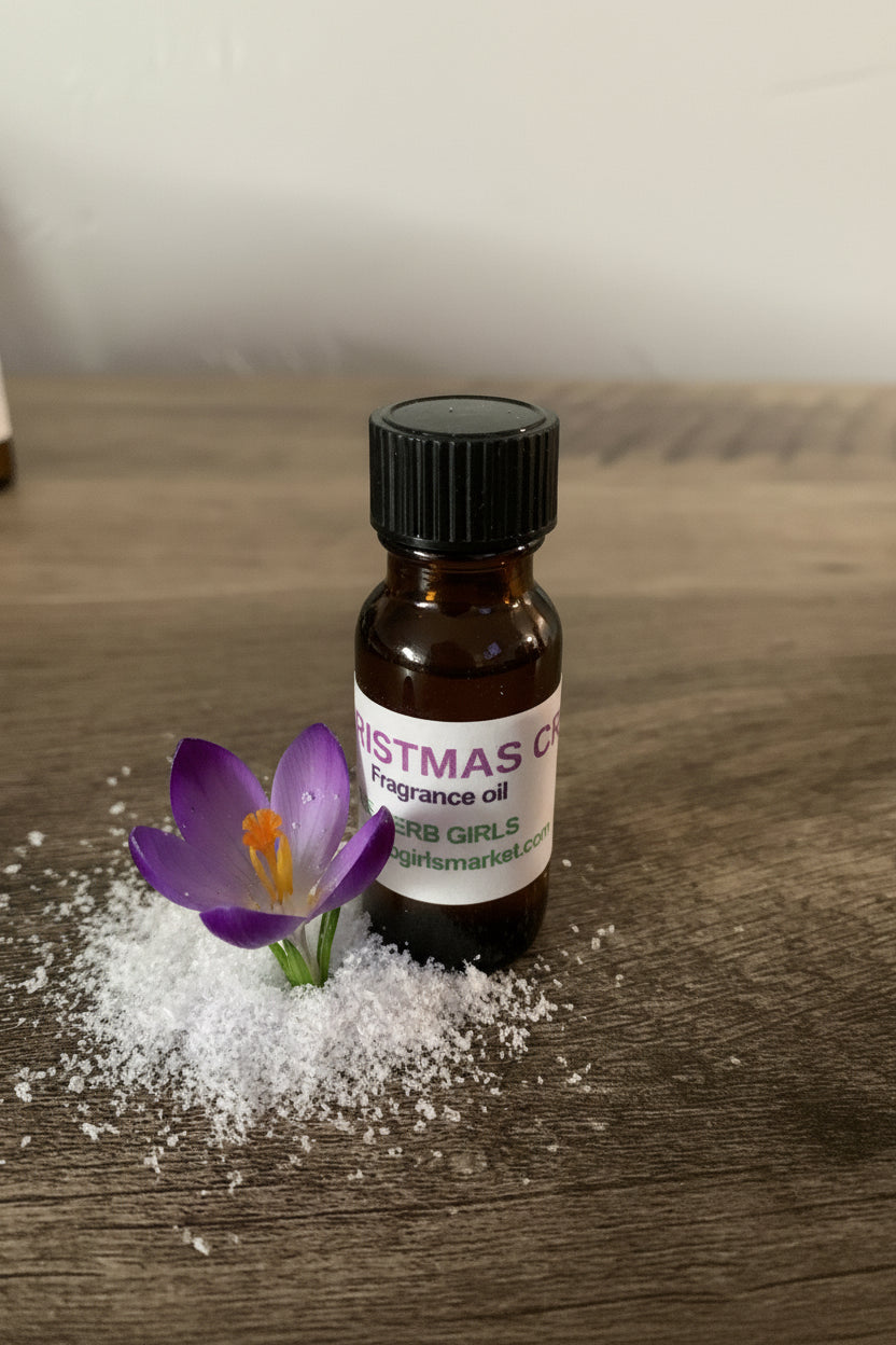 A small amber glass bottle of Christmas crocus fragrance oil with a black cap and a white label, placed on a wooden surface beside a purple crocus flower and white snow.