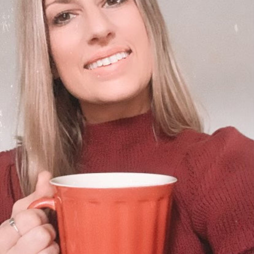 Woman holding an orange mug against a plain background